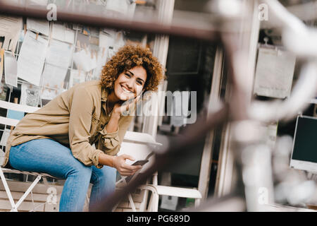 Woman in front of coffee shop, holding smart phone Stock Photo