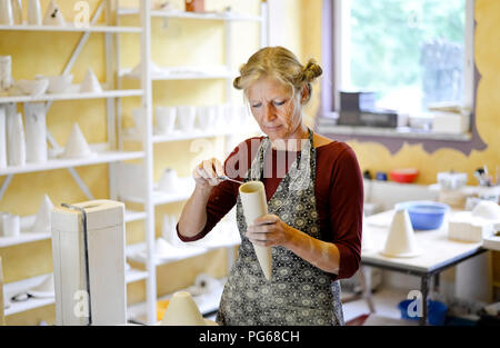 Woman working on product in porcelain workshop Stock Photo