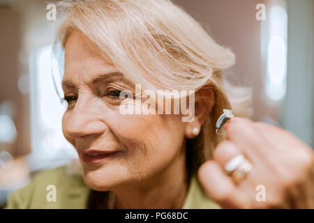 Senior woman applying hearing aid Stock Photo