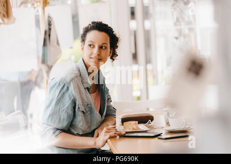 Young woman working in coworking space, eating cake Stock Photo