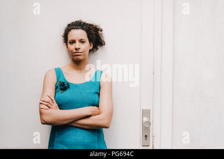Woman crossing arms, standing in front of door Stock Photo