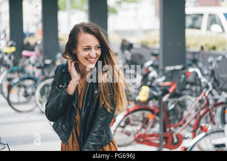 Portrait of happy young woman at bicycle parking station in the city Stock Photo