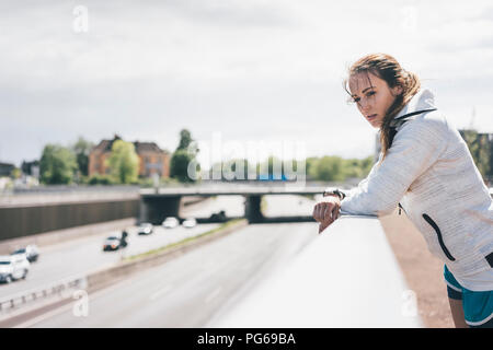 Sportive young woman leaning on railing at motorway Stock Photo