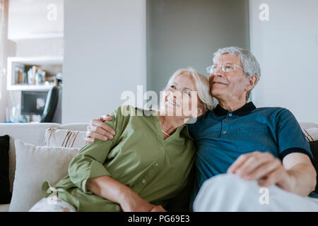 Smiling senior couple sitting on couch at home Stock Photo