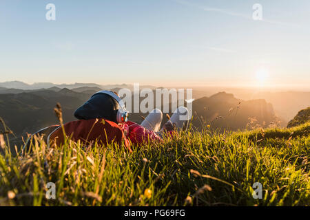 Hiker lying in grass, taking a break and listening music with headphones Stock Photo