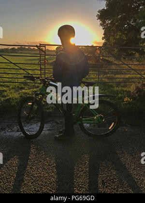 Sunset behind Youth on bicycle, in countryside, at dusk Stock Photo
