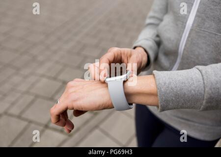 Woman's hand adjusting settings of smartwatch, close-up Stock Photo