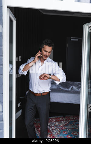 Businessman on cell phone in bedroom at home checking the time Stock Photo