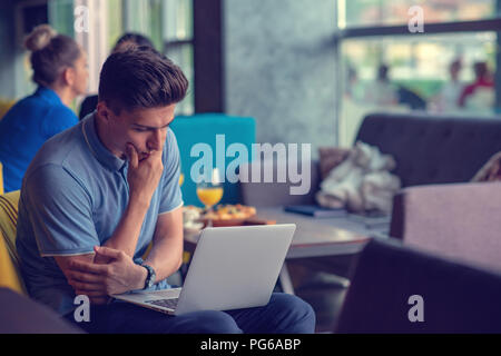 Young skilled male freelancer starting working day early in morning drinking coffee to wake up Stock Photo