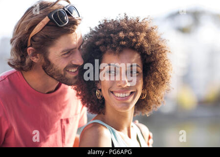 Happy young couple, man whispering into woman's ear Stock Photo