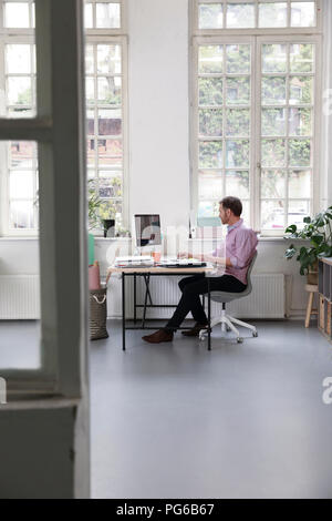 Man working at desk in a loft office Stock Photo