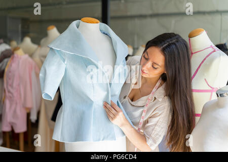 Young fashion designer fitting clothes on dressmaker's model Stock Photo