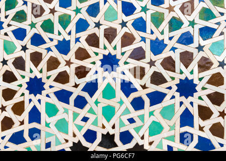 Islamic style tiles forming intricate geometric patterns with blue, white, green, brown and black pieces Stock Photo