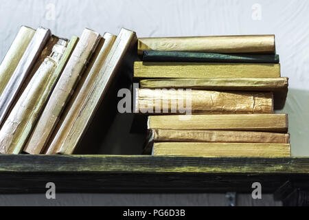 Stack of old books with golden covers on the shelf Stock Photo