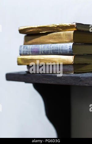 Stack of old books with golden covers on the shelf Stock Photo
