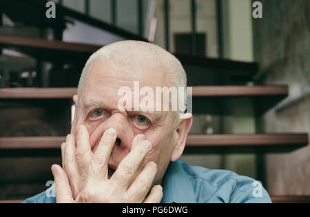 Indoor portrait of an aged man making funny or scary face Stock Photo
