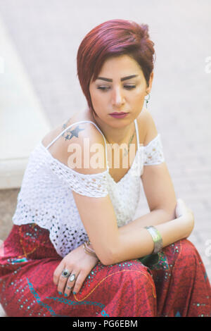 Young woman sat alone in the street Stock Photo