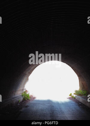 Dark corrugated tunnel and road leading under a French Motorway Autoroute Stock Photo