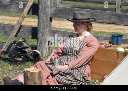 The Confederate Army camping during the American Civil War. Woman drinking from metal mug. Historical reenactment at Appomattox, Virginia. Stock Photo