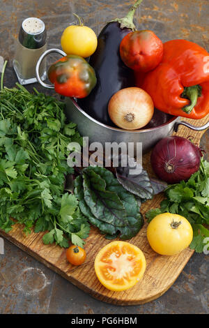 Fresh red pepper , eggplant and onion in pot with tomato, parsley,  coriander mangold  on  iron backgrownd Stock Photo