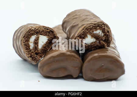 Chocolate covered sponge rolls with the one on top being cut open and laid on its side. Good image for baker confectioner. Stock Photo