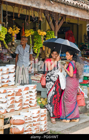 Vertical view of traditionally dressed ladies buying groceries at a fruit and veg stall in Sri Lanka. Stock Photo
