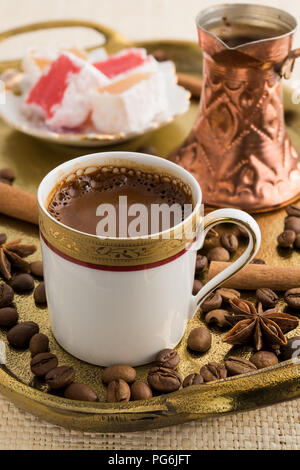 Vintage cup of turkish coffee and traditional bronze coffee pot served in bronze tray with turkish delights, roasted coffee beans, anise stars and cin Stock Photo