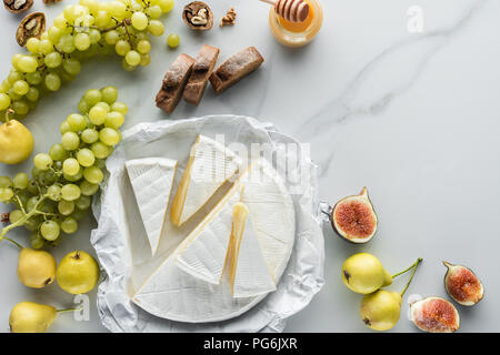 food composition with camembert cheese, grape, honey and bread on white marble surface Stock Photo