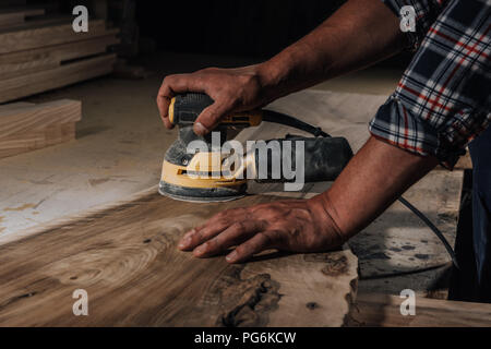 partial view of carpenter working with electric plane at workshop Stock Photo