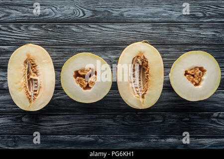 top view of halved ripe sweet melons on wooden surface Stock Photo