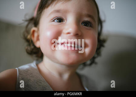 Happy baby girl with big smile sitting on the couch at home Stock Photo