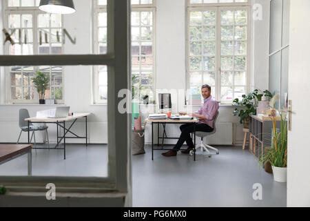 Man working at desk in a loft office Stock Photo