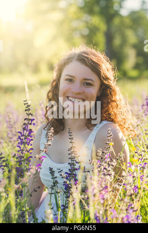 Young woman sitting on summer meadow Stock Photo