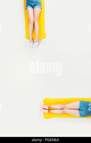 partial top view of people lying on swimming mattresses isolated on white Stock Photo