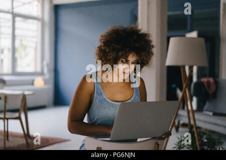Woman working overtime in her start-up business, using laptop Stock Photo