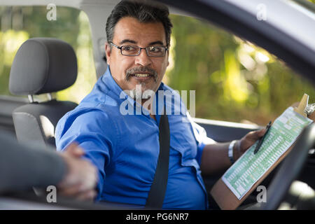 Driving instructor shaking hands with learner driver Stock Photo