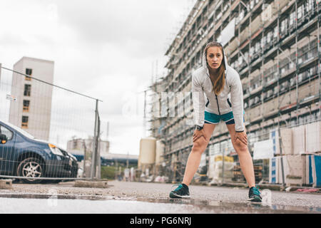 Sportive young woman standing at construction site Stock Photo