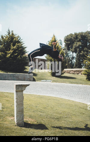 Tattooed man doing parkour in a park Stock Photo