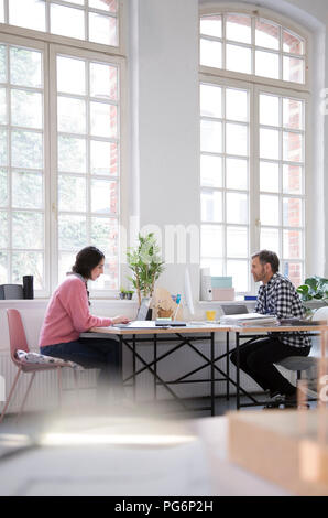 Colleagues working at desk in a loft office Stock Photo