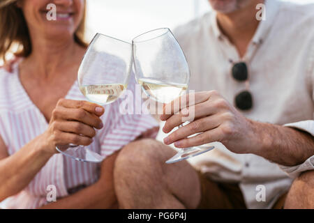 Mature couple drinking wine at sunset on a sailing boat Stock Photo