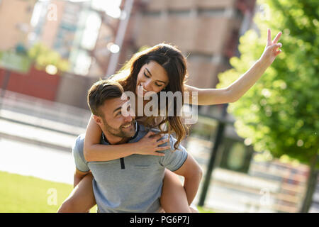 Couple playing piggyback ride in park Stock Photo - Alamy