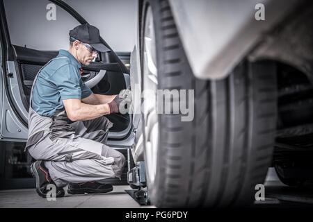 Used Car Under Maintenance. Caucasian Car Mechanic Looking For Potential Problems Inside the Vehicle. Stock Photo