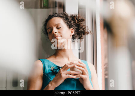 Pretty woman leaning on window, drinking coffee Stock Photo