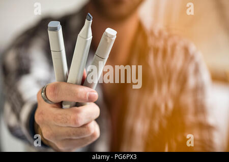 Close-up of artist holding pens Stock Photo