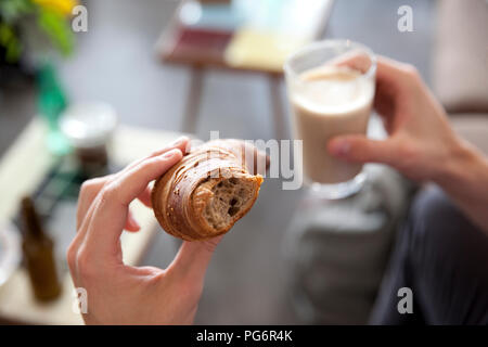 Man's hands holding croissant and  glass of Latte Macchiato Stock Photo