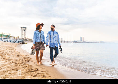 Spain, Barcelona, couple walking barefoot on the beach Stock Photo