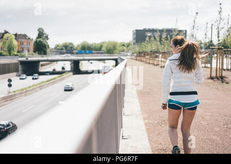 Sportive young woman walking beside motorway Stock Photo