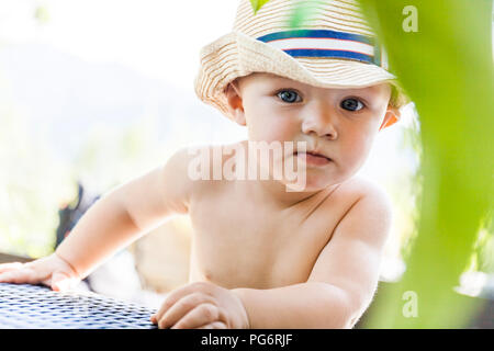 Portrait of curious baby boy wearing straw hat Stock Photo