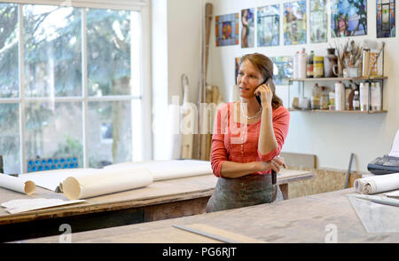 Woman talking on cell phone in glazier's workshop Stock Photo