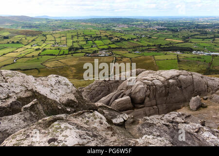 Looking over green fields of County Down countryside from top of rocky crags on Hen Mountain, Mourne Mountains. Stock Photo